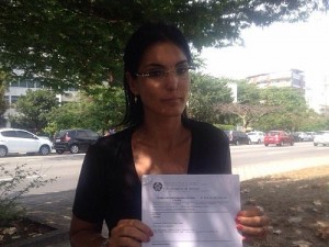 "Indenização é maior que meu salário", diz Luciana Silva Tamburini que, na foto, exibe registro de ocorrência após desentendimento com juiz em Lei Seca